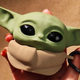 The Mandalorian Grogu Collectible AirPods Pro Case being held in someone's hand against a brown background.